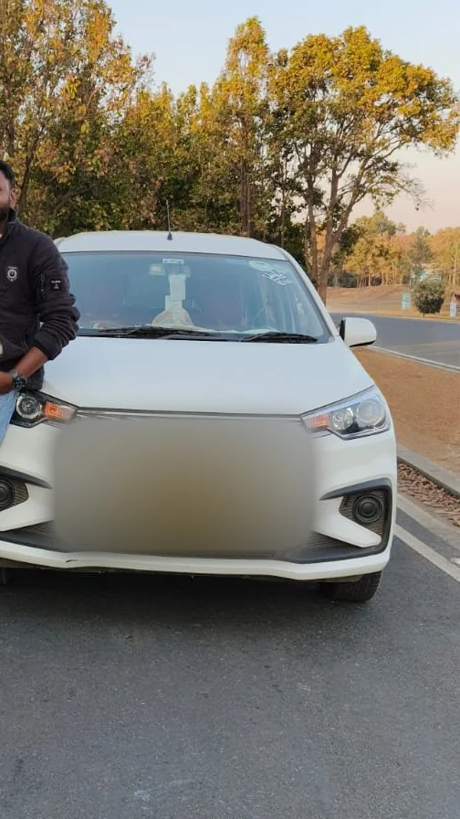 White Ertiga halted on a tree-lined highway